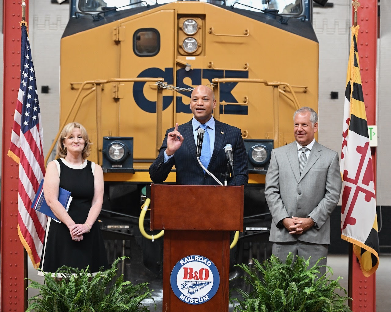 Governor Moore standing at podium with B&O Railroad Museum Executive Director Kris Hoellen and CSX CEO Joe Hinrichs