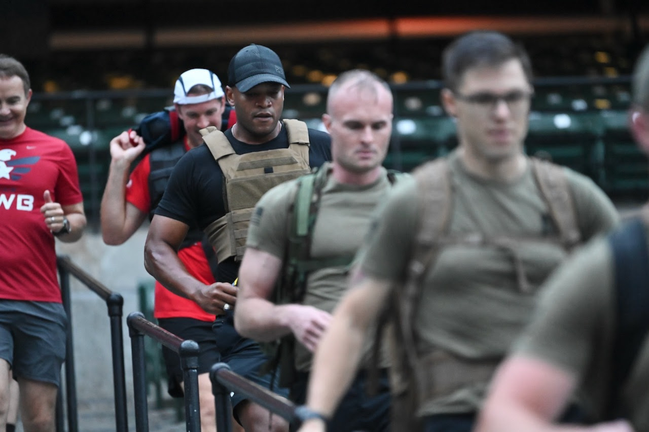 Governor Wes Moore climbs the stairs at Camden Yards with veterans and service members